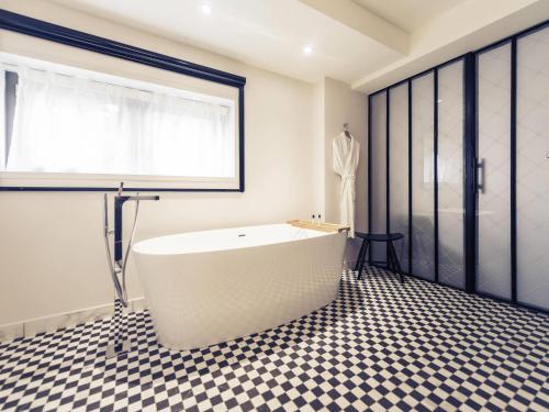 a white bath tub in a bathroom with a checkered floor at Mercure Nantes Centre Gare in Nantes