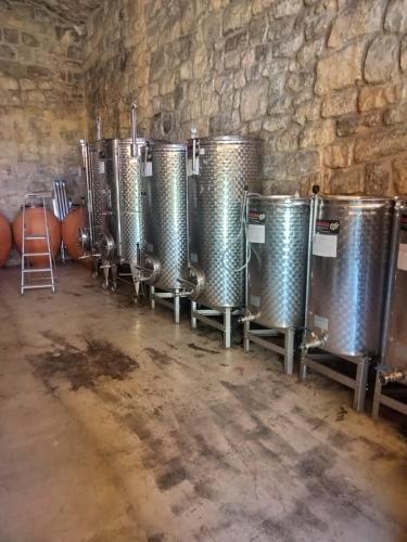 a row of wine barrels lined up against a stone wall at Hostal Boutique Restaurante El Algars in Caseras