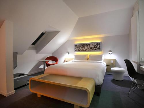 a bedroom with a large white bed and a table at Mercure Nantes Centre Gare in Nantes