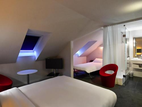 a bedroom with a white bed and red chairs at Mercure Nantes Centre Gare in Nantes