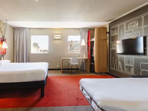 a hotel room with two beds and a flat screen tv at Hotel ibis Rennes Centre Gare Sud in Rennes