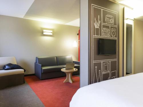 a room with a bed and a couch and a tv at Hotel ibis Rennes Centre Gare Sud in Rennes