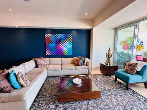 a living room with a couch and a blue wall at 3-Bedroom Condo in the romantic zone in Puerto Vallarta