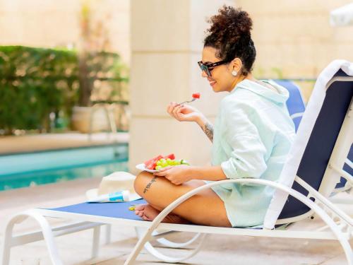 a woman sitting in a chair eating a bowl of fruit at Mercure Sao Paulo Moema Times Square in Sao Paulo