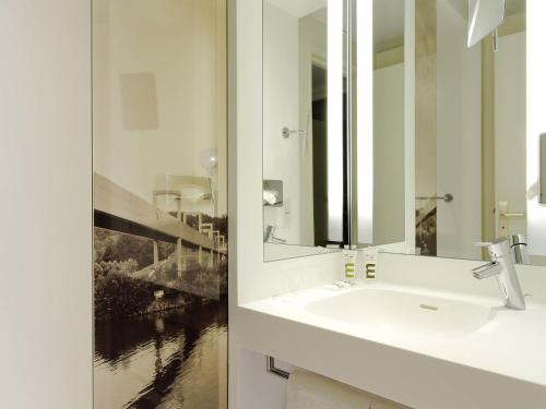 a white bathroom with a sink and a mirror at Mercure Cergy Pontoise Centre in Cergy