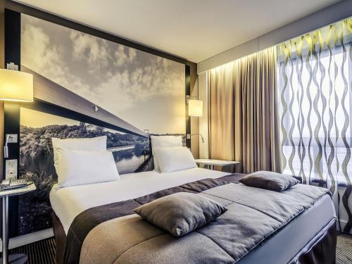 a hotel room with a large bed and a large window at Mercure Cergy Pontoise Centre in Cergy
