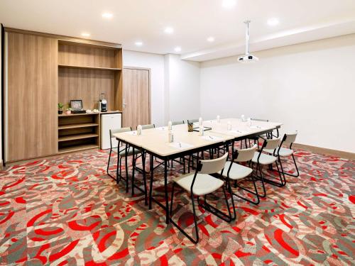 a conference room with a long table and chairs on a carpet at Mercure Sao Paulo Moema Times Square in Sao Paulo