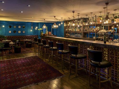 a bar with a row of stools in a restaurant at Mercure Sao Paulo Moema Times Square in Sao Paulo
