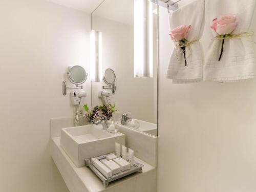 a white bathroom with a sink and a mirror at Mercure Sao Paulo Moema Times Square in Sao Paulo