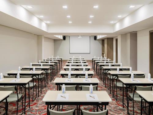 a classroom filled with tables and chairs with a whiteboard at Mercure Sao Paulo Moema Times Square in Sao Paulo