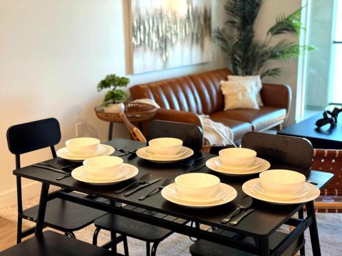a black table with white dishes on it in a living room at Luxury Haven 10 Min From Disneyland With Pool & GYM in Tustin
