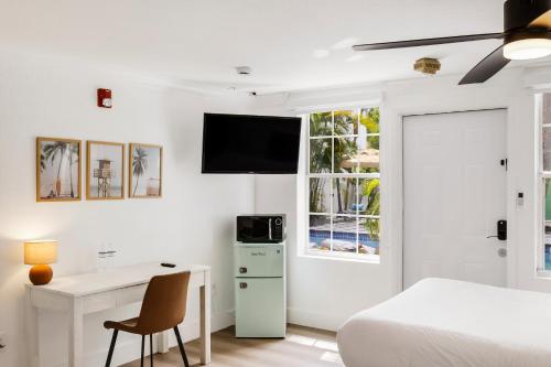a bedroom with a bed and a desk and a tv at The Victoria Hotel in Fort Lauderdale