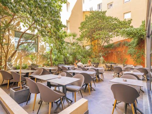 an outdoor restaurant with tables and chairs and trees at Novotel Suites Cannes Centre in Cannes