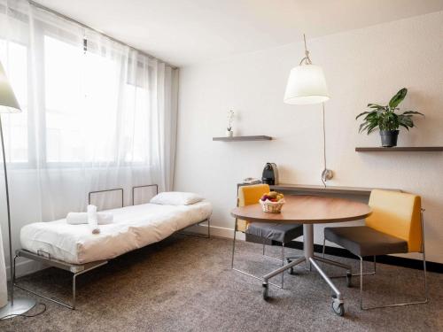 a bedroom with a bed and a table and a desk at Novotel Suites Cannes Centre in Cannes