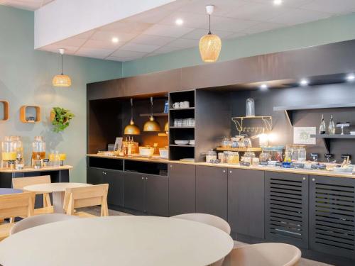 a restaurant with a counter with tables and chairs at Novotel Suites Cannes Centre in Cannes