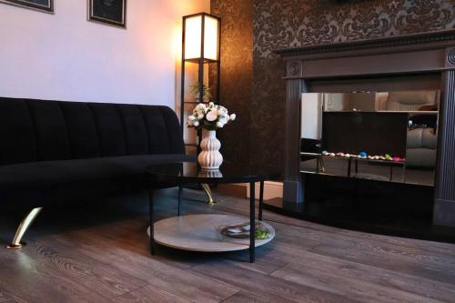 a living room with a couch and a table with a fireplace at Blooming 2 bedroom Property in Beeston Hill