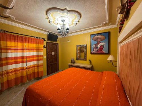 a bedroom with an orange bed and a chandelier at Hotel Boutique La Casa de María Joyita in Aguascalientes