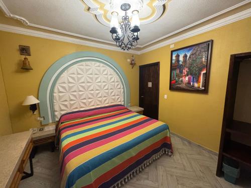 a bedroom with a colorful bed and a chandelier at Hotel Boutique La Casa de María Joyita in Aguascalientes