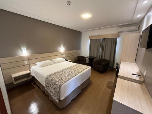 a hotel room with a bed and a chair at Executivos Hotel in Cruz Alta