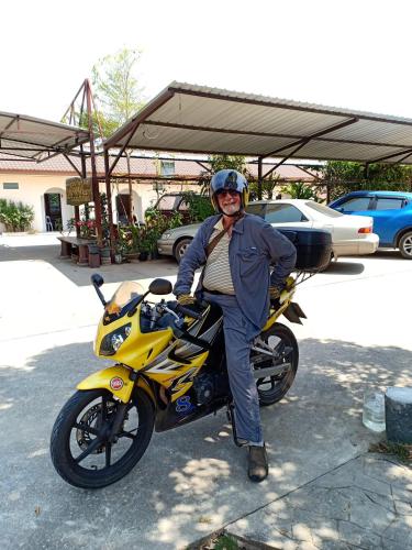 a man is sitting on a yellow motorcycle at Banana Resort Sadao in Sadao