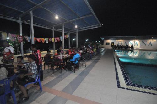 a group of people sitting at tables next to a swimming pool at Banana Resort Sadao in Sadao