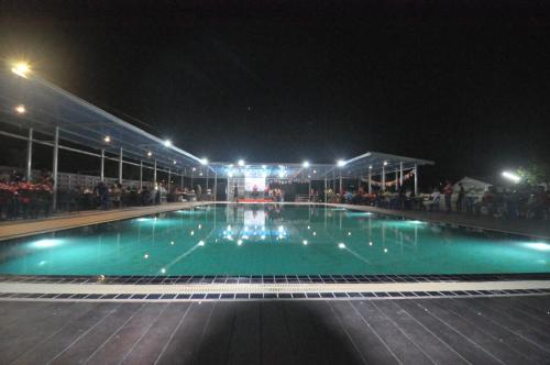 a swimming pool at night with people standing around it at Banana Resort Sadao in Sadao
