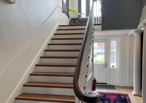 a staircase in a home with white walls and wooden steps at Blind Tiger Portland - Danforth Street Guest House in Portland