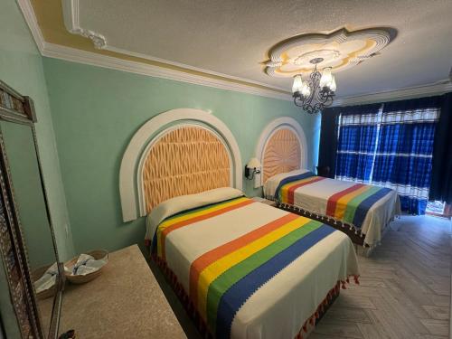 a bedroom with two beds with rainbow at Hotel Boutique La Casa de María Joyita in Aguascalientes