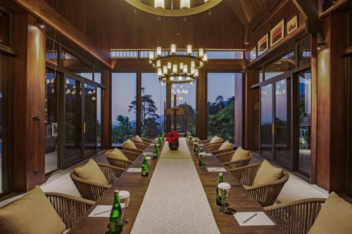 a long table in a restaurant with chairs and a chandelier at Plataran Puncak Suites in Puncak