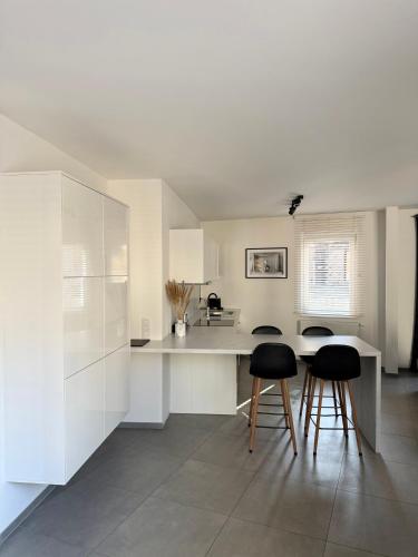 a kitchen with white cabinets and black stools at Appartement au coeur de Spa avec parking privé in Spa