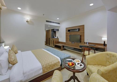 a bedroom with a bed and a tv and a chair at Hotel D Fairmount Plaza Near IGI in New Delhi