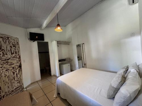 a bedroom with a white bed and a tv at Pousada Arraial dos Sonhos in Arraial d'Ajuda