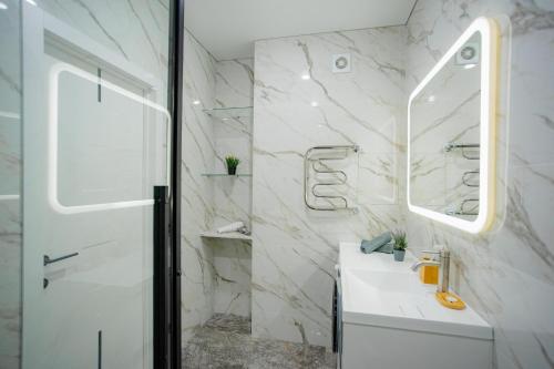 un bagno bianco con lavandino e specchio di 1 комнатная квартира в новом ЖК Панорама Парк по улице Темирбаева 50 a Qostanay