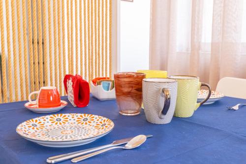een blauwe tafel met borden, kopjes en lepels erop bij B&B Napoli Centro in Napels