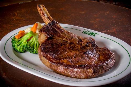 a plate with a steak and broccoli on a table at La Siesta Hotel in Hermosillo