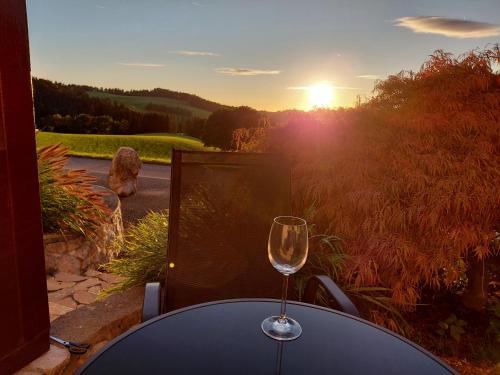 a glass of wine sitting on a table with the sunset at Wohnung im ländlichen Flair in Bad Zell