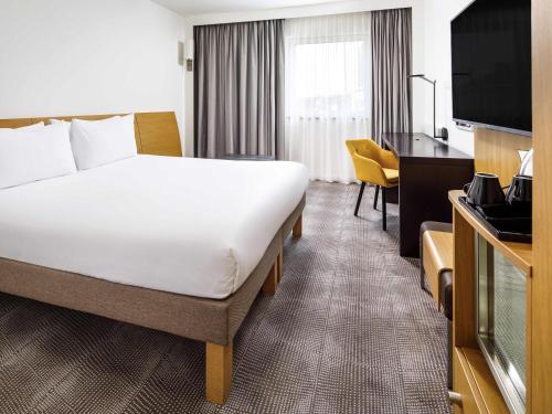 a hotel room with a bed and a television at Novotel London Greenwich in London