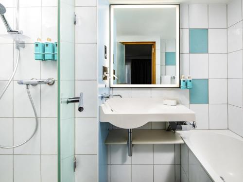 a bathroom with a sink and a mirror at Novotel London Greenwich in London
