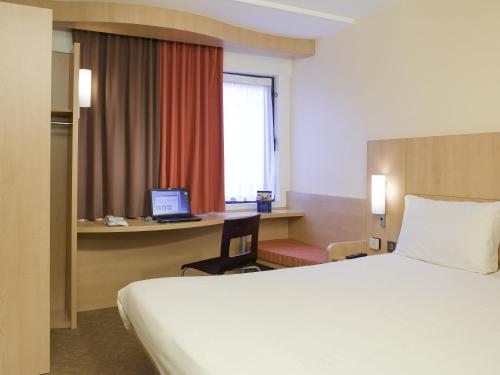 a hotel room with a bed and a desk with a computer at ibis Hull City Centre in Hull