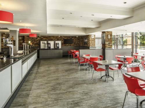 a restaurant with red chairs and tables in a room at ibis Hull City Centre in Hull