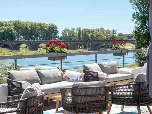 a patio with wicker chairs and a couch on a balcony at Mercure Nevers Pont De Loire in Nevers