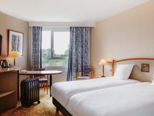 a hotel room with a bed and a desk and a window at Mercure Nevers Pont De Loire in Nevers