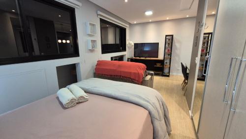 Un pequeño dormitorio con una cama y un televisor. en Studio Aconchegante Jd Botânico, en Curitiba