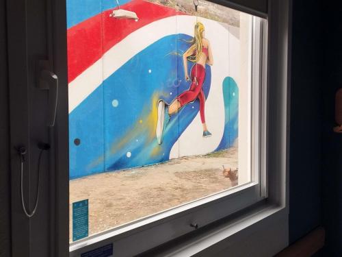 a window with a painting of a woman on a surfboard at ibis budget Alicante Pension sin comedor in Alicante