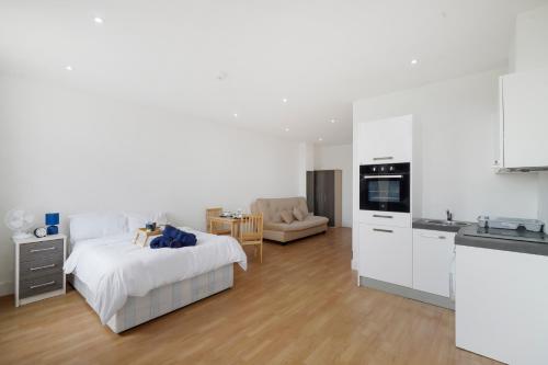 a white bedroom with a bed and a kitchen at Private Studio Apartment with Parking in Borehamwood