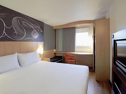a hotel room with a large white bed and a window at ibis Liège Seraing in Boncelles