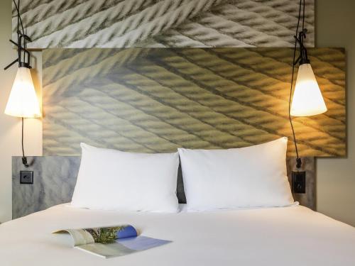a bed with two pillows and a book on it at ibis Genève Aéroport in Geneva