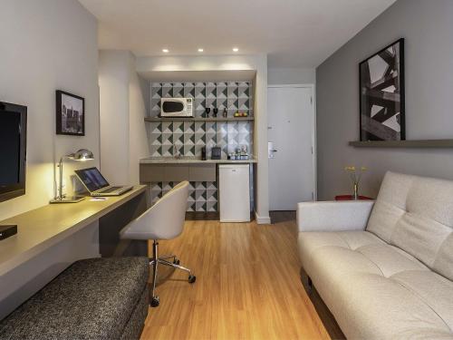 a living room with a couch and a desk at Mercure Sao Paulo Moema in Sao Paulo
