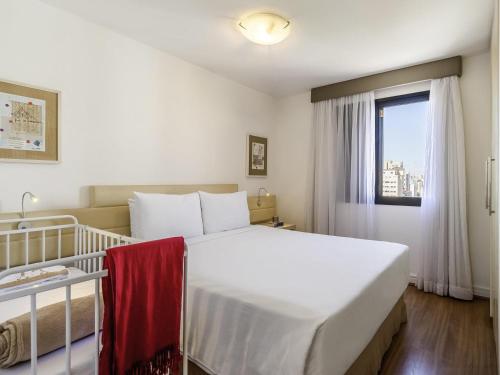 a bedroom with a large white bed and a window at Mercure Sao Paulo Moema in Sao Paulo