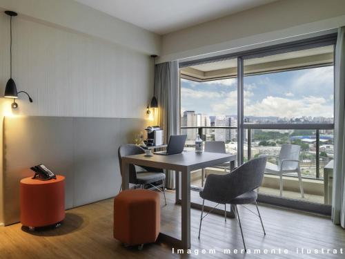a room with a table and chairs and a window at Mercure Sao Paulo Moema in Sao Paulo